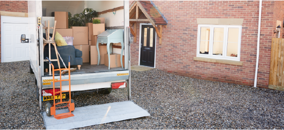 junk removal truck full of furniture and boxes in front of house