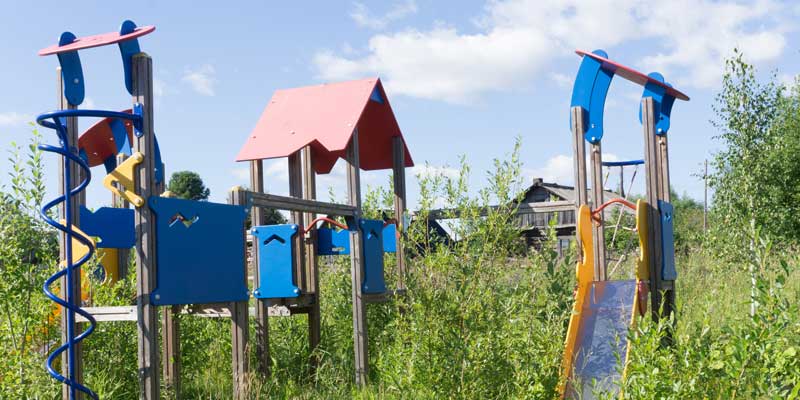 Old broken play set in overgrown yard