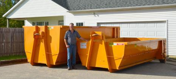 Man standing next to a 10 yard and 20 yard dumpster