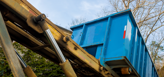 roll-off container being unloaded by dumpster truck