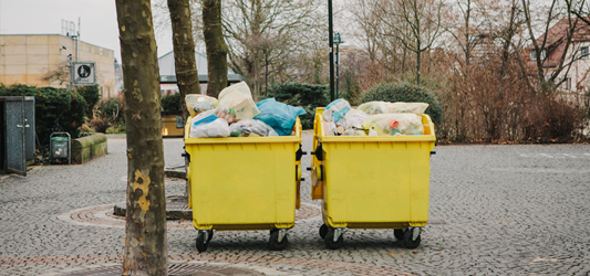 Two commercial dumpsters on wheels full of trash