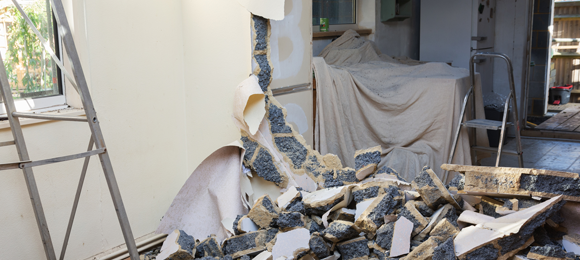 Drywall and insulation being torn out of a interior kitchen wall