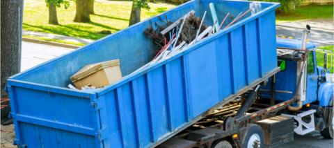 blue dumpster being loaded onto truck