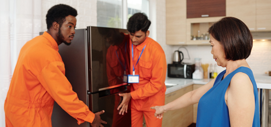 Two junk removal workers removing a refrigerator