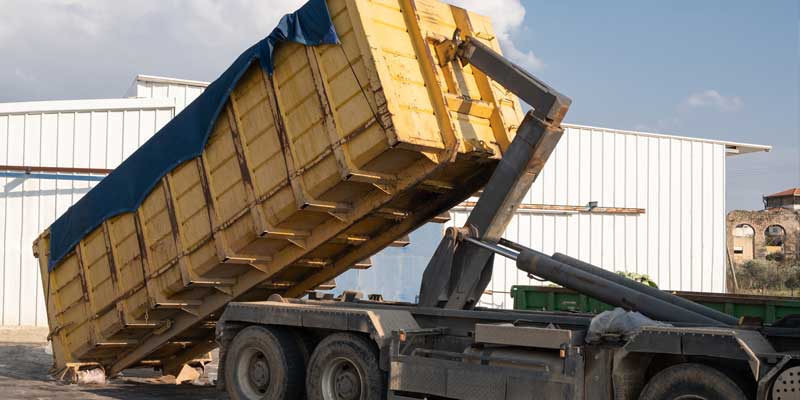 Dumpster truck delivering a roll-off container