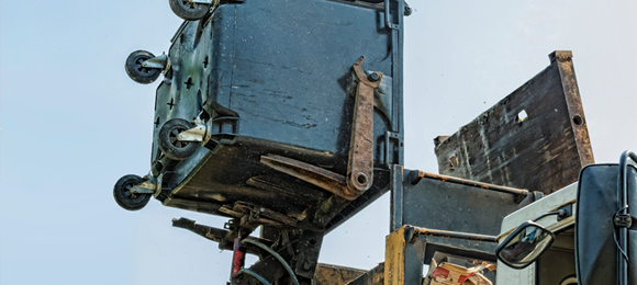 blue dumpster being emptied into a dump truck