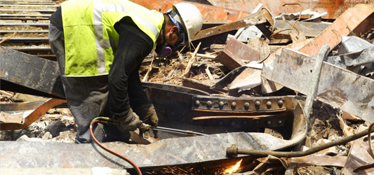 pro wearing PPE cutting up scrap metal