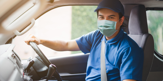 junk removal worker wearing mask driving hauling truck