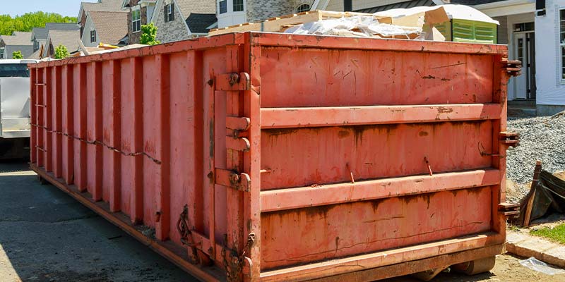 full dumpster sitting in front of residential homes