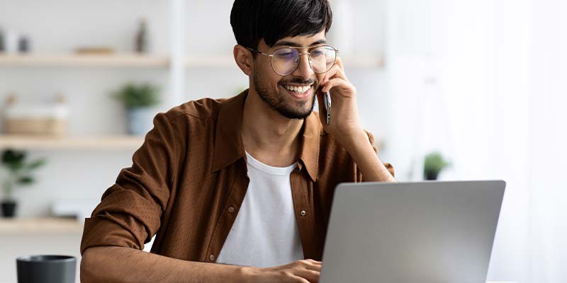 man on phone looking at computer