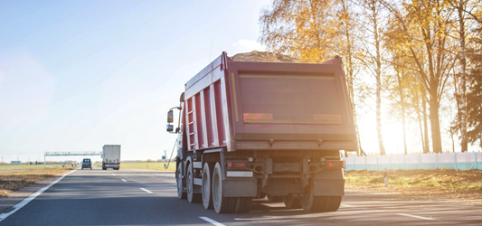 Dump truck driving with full dumpster