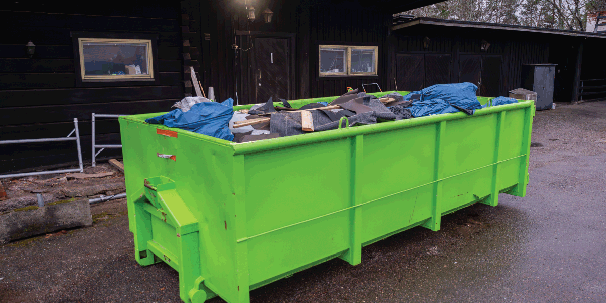 green dumpster full of renovation debris