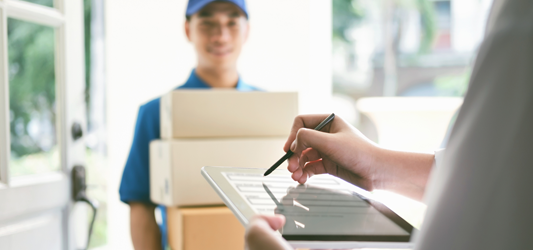 Person signing digital invoice while junk removal worker holds boxes