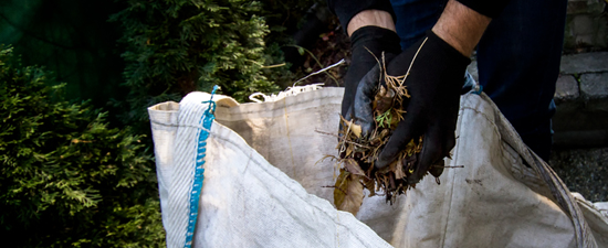 adding leaves to a reusable yard waste bag