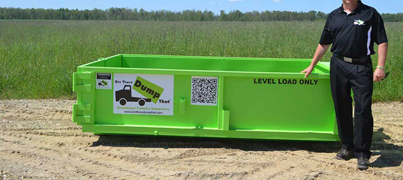 waste disposal professional standing next to a 4 yard mini roll-off dumpster