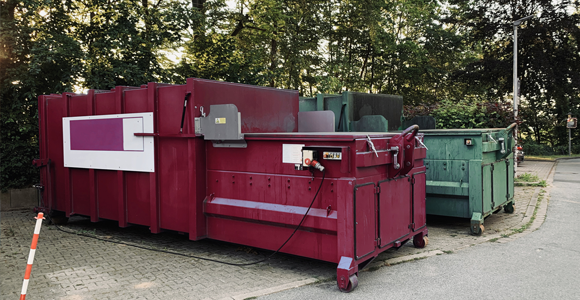 red and green commercial trash compactors sitting side by side