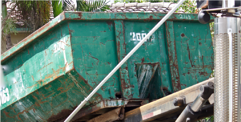 green roll-off dumpster being rolled off truck