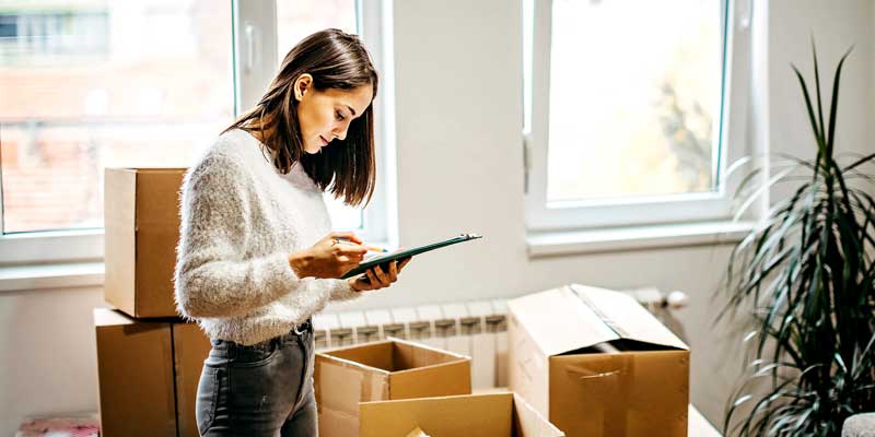 woman looking at checklist surrounded by packing boxes