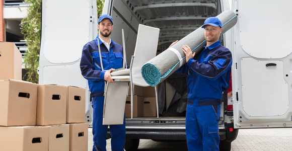 Junk removal crew loading carpet and other furniture into hauling vehicle