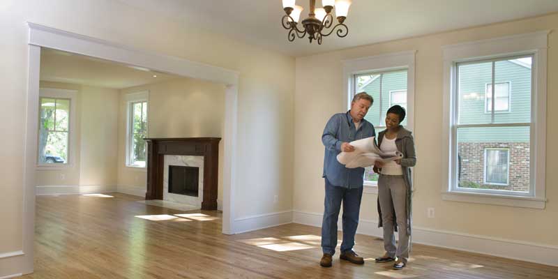 Couple looking at blueprint in empty home