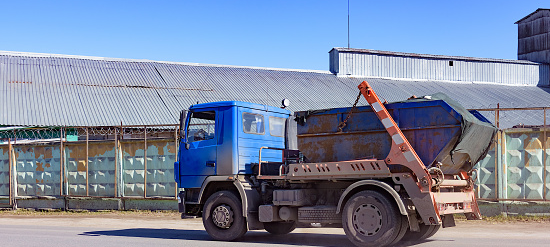 dumpster being driven away on truck