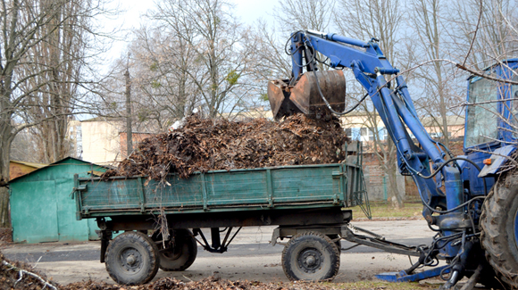 Excavator dumping yard debris into trailer dumpster