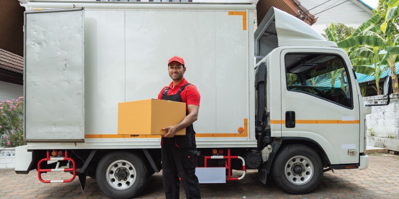 man holding a box in front of junk removal truck