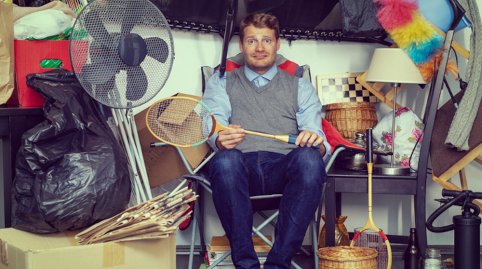 overwhelmed man sitting in cluttered garage