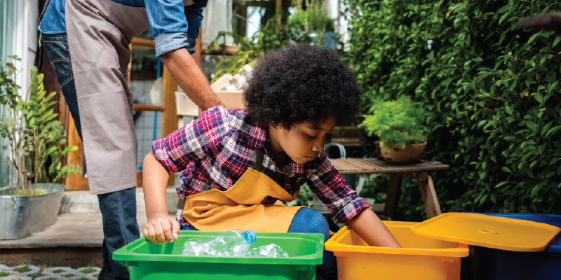 young boy and father placing plastic water bottles into recycling bin