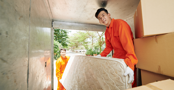 Junk removal crew loading mattress into box truck