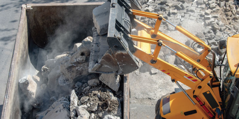 heavy debris loaded into dumpster by excavator