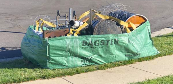 Bagster filled with materials by sidewalk