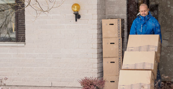 Junk removal worker hauling items outside of a home while it's snowing